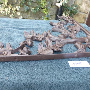 May include: A brown metal shelf bracket with an intricate design of oak leaves and acorns. The bracket is labeled "Front".