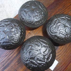 May include: Four black cast iron door knobs with intricate swirling patterns.