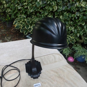 May include: Black vintage desk lamp with a curved shade and a black cord. The lamp is sitting on a white surface with the number 6933C written on a white tag.