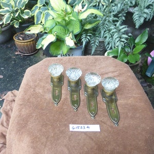 May include: Four antique brass door knobs with clear glass crystal knobs. The knobs are on a brown surface with a white tag that says "G15234".