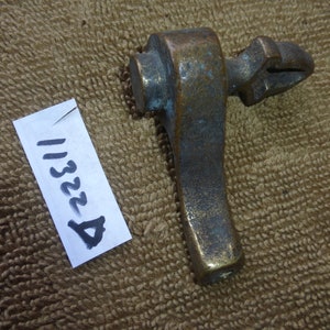 May include: A brass lever with a hook on the end. The lever is about 6 inches long and has a worn, aged finish.