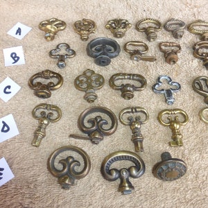 May include: Assortment of antique-style keyhole escutcheons and keys in various designs and finishes, including brass, silver, and gold.