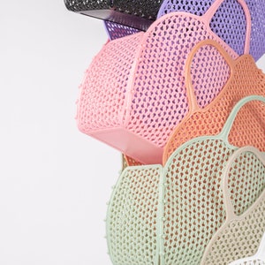 Pu&ograve; includere: Una pila di cinque cesti di plastica intrecciati colorati. I cesti sono in tonalit&agrave; di nero, viola, rosa, verde e bianco. I cesti hanno tutti la stessa forma e un motivo intrecciato.