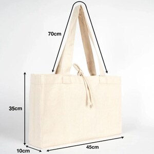 Op de afbeelding: Een natuurlijke canvas draagtas met lange handvatten. De tas is rechthoekig en meet 45 cm lang, 35 cm hoog en 10 cm breed. De handvatten zijn 70 cm lang. De tas heeft een trekkoordsluiting.