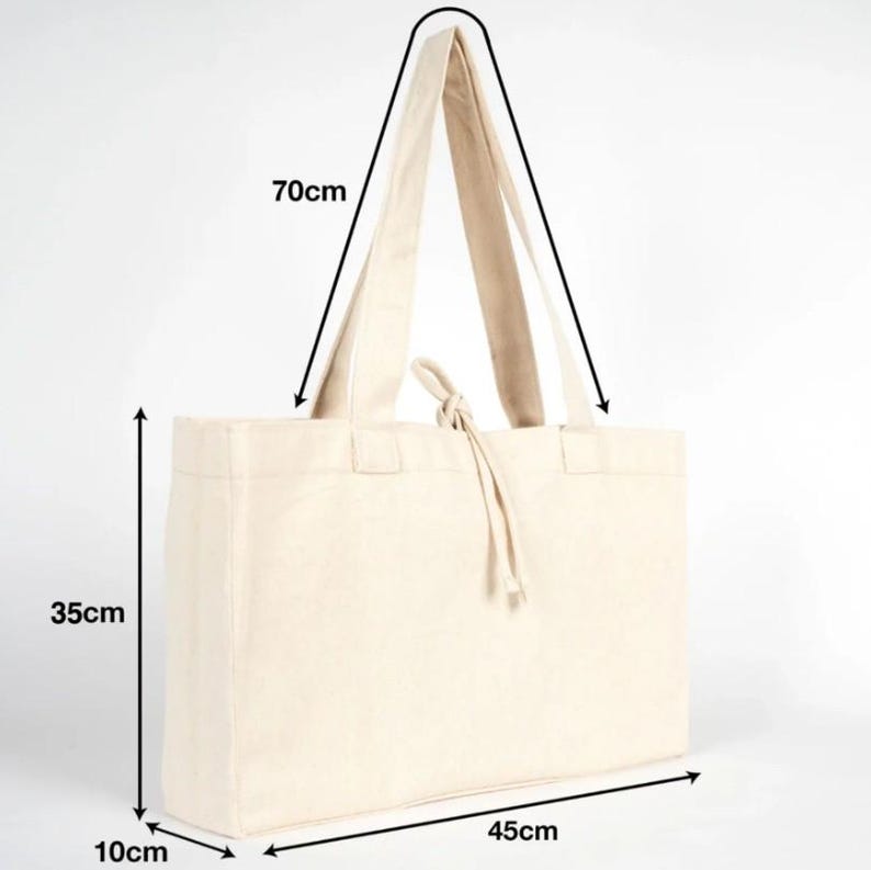 Op de afbeelding: Een natuurlijke canvas draagtas met lange handvatten. De tas is rechthoekig en meet 45 cm lang, 35 cm hoog en 10 cm breed. De handvatten zijn 70 cm lang. De tas heeft een trekkoordsluiting.