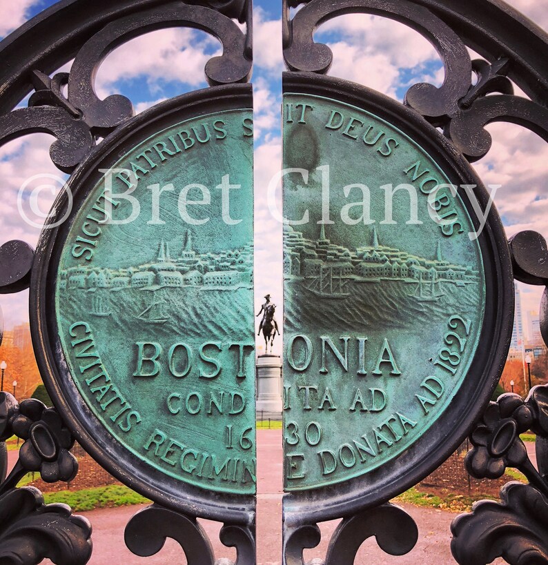 Puede incluir: Primer plano de una puerta de bronce con el sello de la ciudad de Boston. El sello presenta un paisaje urbano detallado y el texto "BOSTONIA CONDITA AD 1630 CIVITATIS REGIMINE DONATA AD 1822". La puerta est&aacute; enmarcada por una ornamentada herrer&iacute;a oscura.