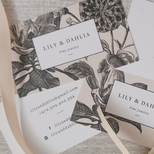 May include: Two business cards with a floral design. The text on the cards reads "LILY & DAHLIA Fine Jewelry" and includes contact information for the business.