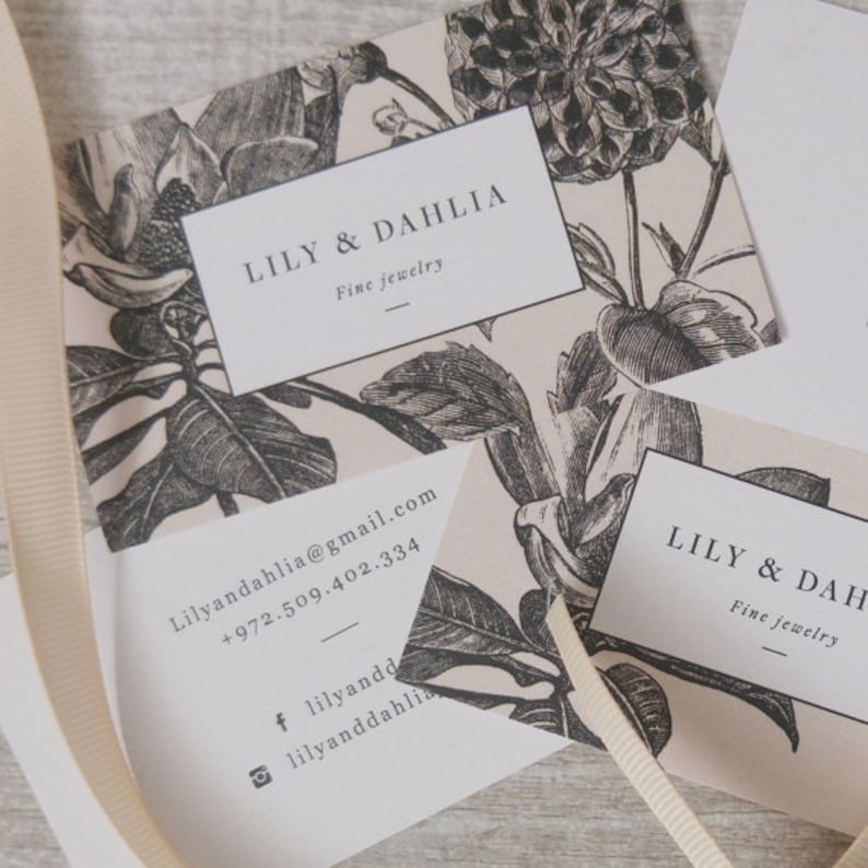 May include: Two business cards with a floral design. The text on the cards reads "LILY & DAHLIA Fine Jewelry" and includes contact information for the business.