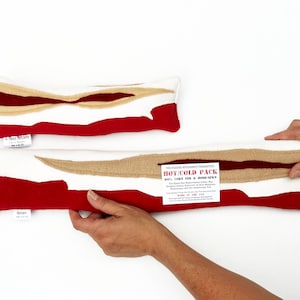 May include: Two red and beige fabric hot and cold packs shaped like a slice of bacon. The larger pack has a label that reads "The Plaid Butcher's Guaranteed Hot/Cold Pack 100% Cotton Filled & Home Sewn".