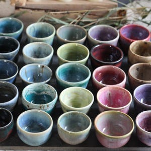 May include: A set of three ceramic mugs with a speckled, matte finish. The mugs are in shades of cream, light gray, and dark gray. Each mug has a simple, minimalist design and a rounded handle. The mugs are suitable for coffee, tea, or other beverages.