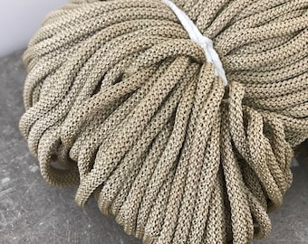 Puede incluir: Primer plano de un gran paquete de cuerda beige. La cuerda está enrollada apretada y tiene una superficie ligeramente texturizada.