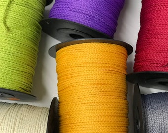 May include: Spools of colorful cord in various colors including green, purple, yellow, beige, red, and gray. The cords are wound around black spools.