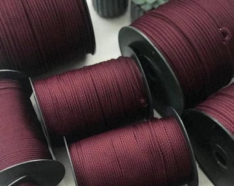 May include: Multiple spools of burgundy colored cord or rope wound around black plastic spools.