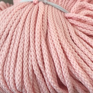 May include: A close-up of a bundle of pink cotton rope. The rope is tightly wound and has a soft, textured surface.
