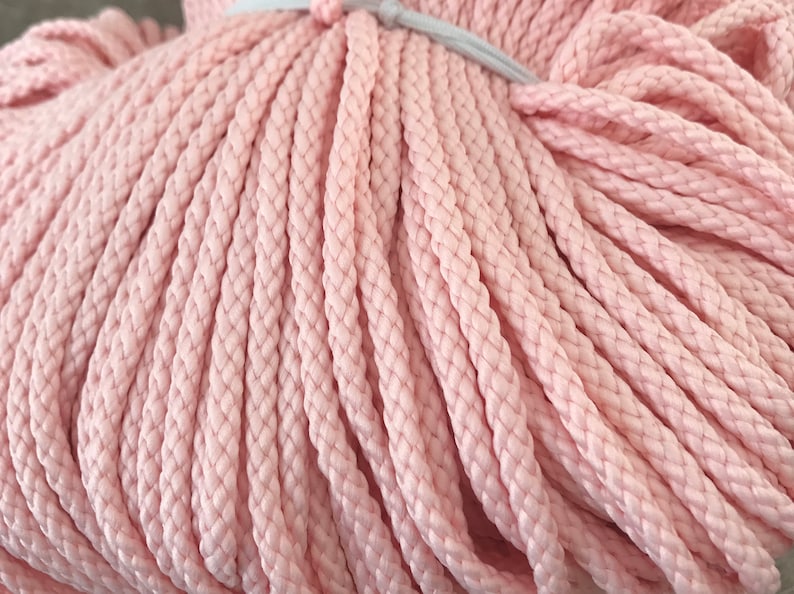 May include: A close-up of a bundle of pink cotton rope. The rope is tightly wound and has a soft, textured surface.