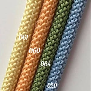 May include: Four different colors of braided cord, from left to right: light yellow, peach, green, and light blue. The cords are labeled with numbers: 061, 060, 064, and 020.