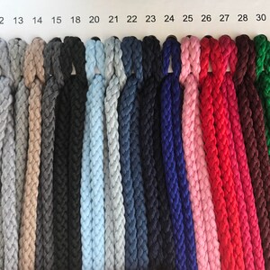 May include: A color chart of 20 different colors of braided rope. The rope is arranged in rows, with each color in a separate row. The colors include yellow, gray, beige, black, light blue, navy blue, dark blue, pink, red, maroon, green, and olive green.