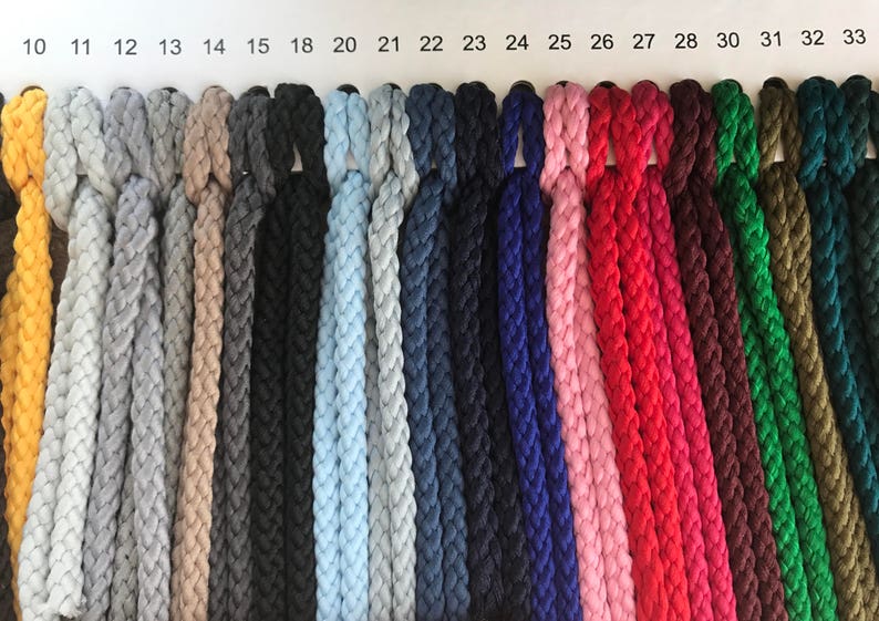 May include: A color chart of 20 different colors of braided rope. The rope is arranged in rows, with each color in a separate row. The colors include yellow, gray, beige, black, light blue, navy blue, dark blue, pink, red, maroon, green, and olive green.
