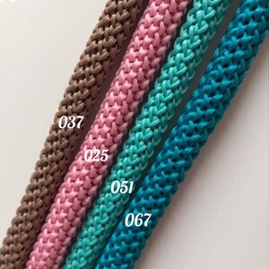 May include: Four different colors of braided cord, from left to right: brown, pink, teal, and turquoise. The cords are labeled with numbers: 037, 025, 051, and 067.
