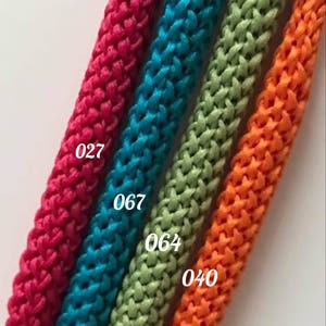 May include: Four spools of braided cord in different colors: red, teal, green, and orange. The spools are labeled with numbers: 027, 067, 064, and 040.