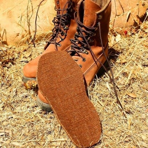 May include: A pair of brown leather boots with laces. The boots are worn and have a brown felt insole.