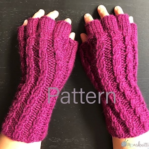 May include: A pair of pink fingerless gloves with a cable knit pattern. The gloves are made with a soft yarn and have a comfortable fit.