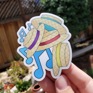 May include: A sticker of a stack of four straw hats with blue, purple, and red accents. The hats are stacked on top of each other and are surrounded by musical notes.