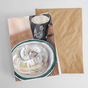 May include: Watercolor illustration of a cake on a plate with a green rim, a black mug with white floral designs, and a brown envelope. The cake is topped with white icing. The mug is filled with a white liquid.