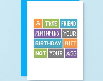 May include: A white greeting card with a blue border. The card features the text "A TRUE FRIEND REMEMBERS YOUR BIRTHDAY BUT NOT YOUR AGE" in colorful block letters. A fun and lighthearted birthday card.
