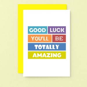May include: A white card with the text "Good Luck You'll Be Totally Amazing" in colorful blocks. The card is surrounded by a yellow border.