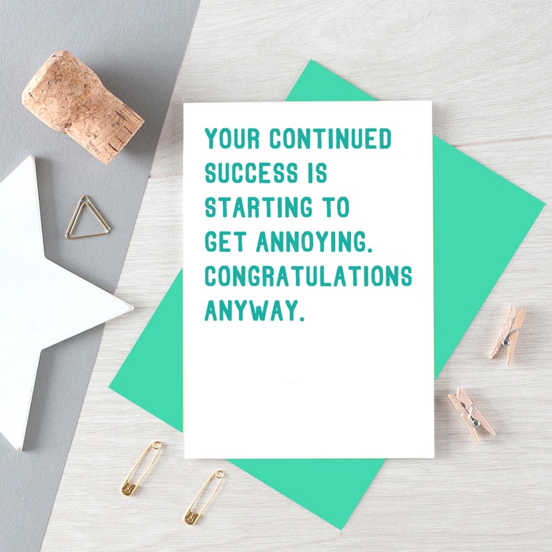 May include: White card with teal text that reads "Your continued success is starting to get annoying. Congratulations anyway."