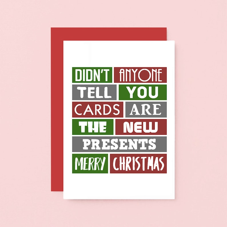 Pu&ograve; includere: Un biglietto d'auguri bianco con una busta rossa che riporta il testo DIDN'T ANYONE TELL YOU CARDS ARE THE NEW PRESENTS MERRY CHRISTMAS in una griglia di blocchi rettangolari verdi, grigi e rossi con caratteri bianchi.