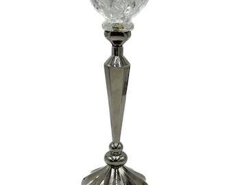 May include: A silver metal candlestick with a clear glass flower-shaped top. The candlestick has a tall, slender base with a decorative design.