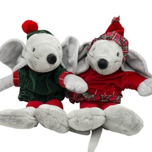 May include: Two plush mouse toys with grey fur, large ears, and black noses. One mouse wears a green velvet top with a red pom-pom hat, while the other wears a red velvet top with a matching red and green plaid hat and skirt trim.