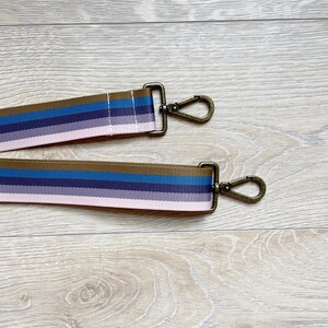 May include: Two brown, pink, blue, and purple striped straps with gold metal clasps.