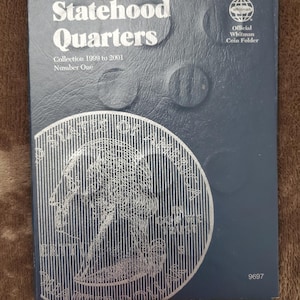 May include: A dark blue Whitman coin folder for Statehood Quarters. The cover features the text "Statehood Quarters" and "Collection 1999 to 2001 Number One." A large silver coin design is visible on the front.