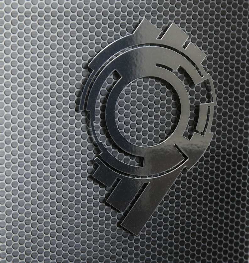 May include: A silver metallic number nine with a circular design, set against a black background with a hexagonal pattern.