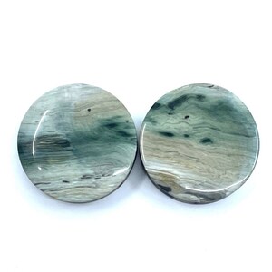 May include: Two round, green and white agate coasters with a swirling pattern.
