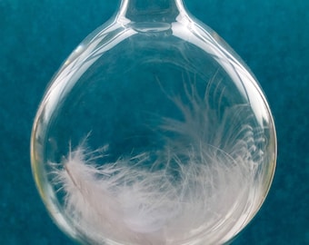 After a death, a tender gift for a grieving heart, a blown glass tear drop with one white angel feather inside with tender words of comfort.