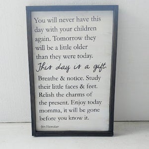 May include: Black framed sign with white text that reads "You will never have this day with your children again. Tomorrow they will be a little older than they were today. This day is a gift. Breathe & notice. Study their little faces & feet. Relish the charms of the present. Enjoy today momma, it will be gone before you know it. -Jen Hatmaker"