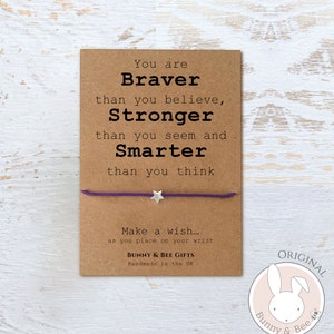 May include: A purple string bracelet with a silver star charm. The card attached to the bracelet reads "You are Braver than you believe, Stronger than you seem and Smarter than you think. Make a wish... as you place on your wrist. Bunny & Bee Gifts. Handmade in the UK."