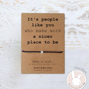 May include: A brown card with the text "It's people like you who make work a nicer place to be."  A black string bracelet with a silver star charm is attached to the card. The card also has the text "Make a wish... as you place on your wrist" and "Bunny & Bee Gifts Handmade in the UK". A pink circle with a white bunny and bee logo and the text "ORIGINAL Bunny & Bee" is in the bottom right corner.
