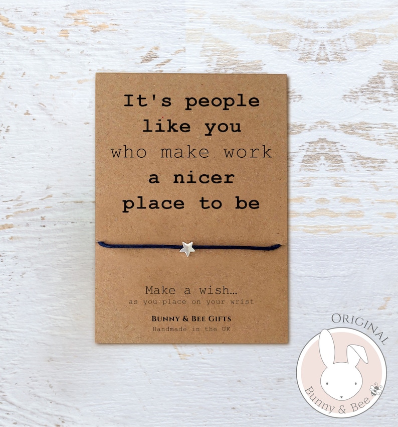 May include: A brown card with the text "It's people like you who make work a nicer place to be."  A black string bracelet with a silver star charm is attached to the card. The card also has the text "Make a wish... as you place on your wrist" and "Bunny & Bee Gifts Handmade in the UK". A pink circle with a white bunny and bee logo and the text "ORIGINAL Bunny & Bee" is in the bottom right corner.