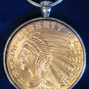 May include: A gold-toned pendant necklace featuring a replica of a 1929 Indian Head penny. The coin features a profile of a Native American wearing a headdress, the word "LIBERTY" above, and the year "1929" below.