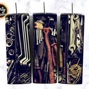 May include: Three stainless steel tumblers with a toolbox full of tools design. The tumblers are black and have a metallic finish. The tools are arranged in a random pattern and include wrenches, screwdrivers, pliers, and other tools.