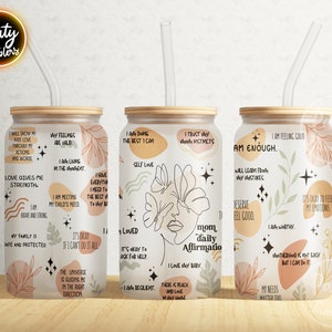 May include: Three stainless steel tumblers with a wood lid and a clear straw. Each tumbler features a different design with abstract shapes, flowers, and stars. The tumblers have positive affirmations printed on them, such as "I am enough", "Love gives me strength", and "I am doing the best I can".