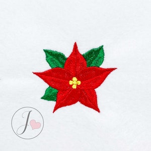 Puede incluir: Poinsettia roja bordada con hojas verdes, una flor tradicional de Navidad.