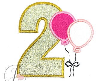 Puede incluir: Número dos de purpurina dorada con dos globos rosa y blanco unidos con una cinta negra.
