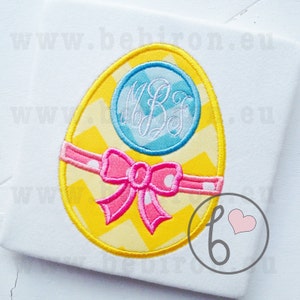 May include: A yellow Easter egg with a chevron pattern and a pink bow. A blue circle with white monogram letters "MBJ" is on the egg.