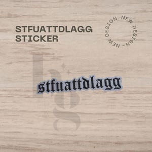 May include: A sticker with the text "STFUATTDLAGG" in a gothic font. The word "STICKER" is above the text. The sticker is on a light wood grain background. A circular design with the words "NEW DESIGN" is also visible.